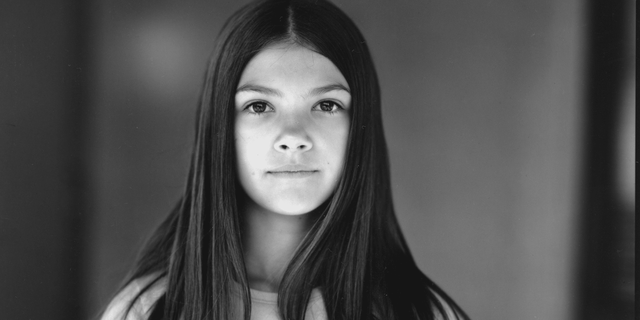 Black and white image of a young girl white long dark hair.