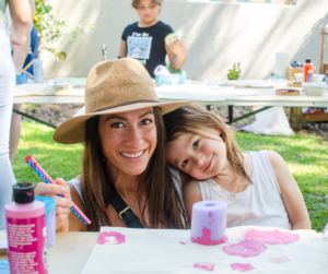 Mother and young daughter smiling together at an arts and craft table.
