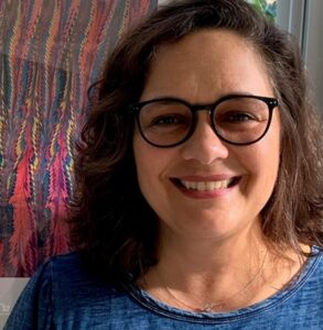 A headshot of Silvana Martins smiling with glasses.