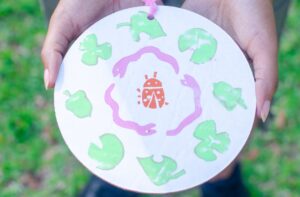 A wooden print with a center lady bug, a ring of snakes, and an outer rings of leaves.