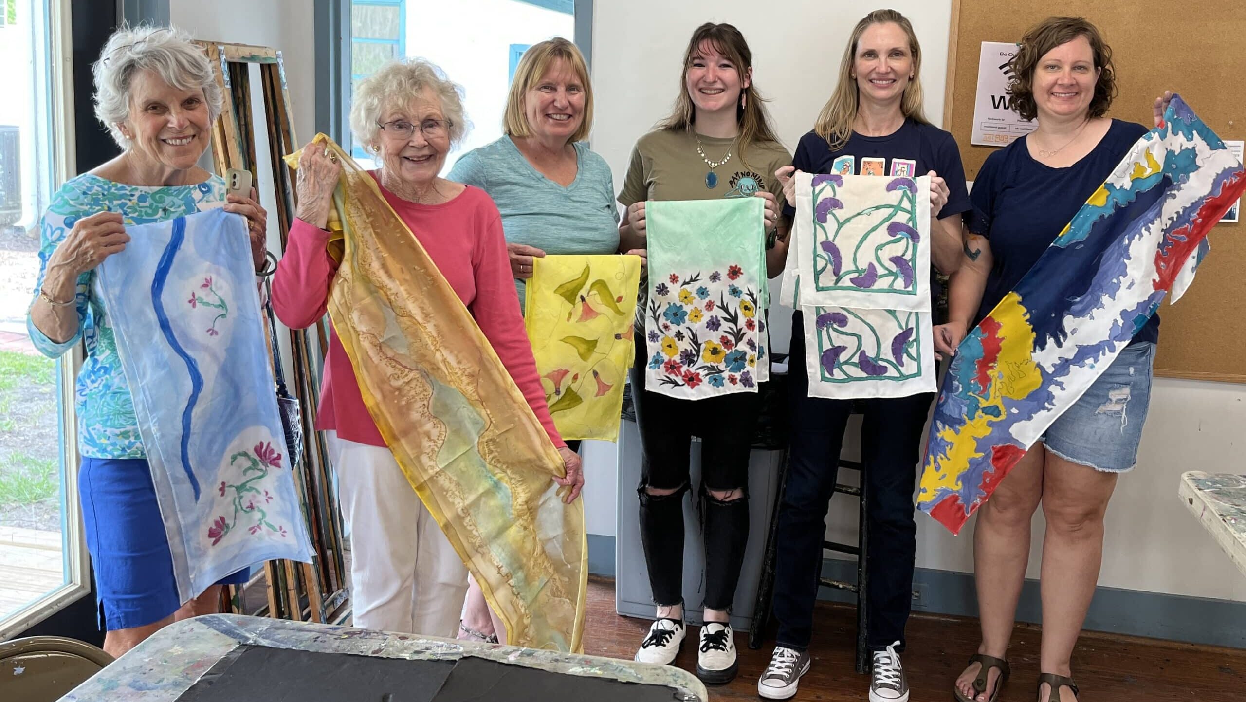 A group of people holding handmade scarves