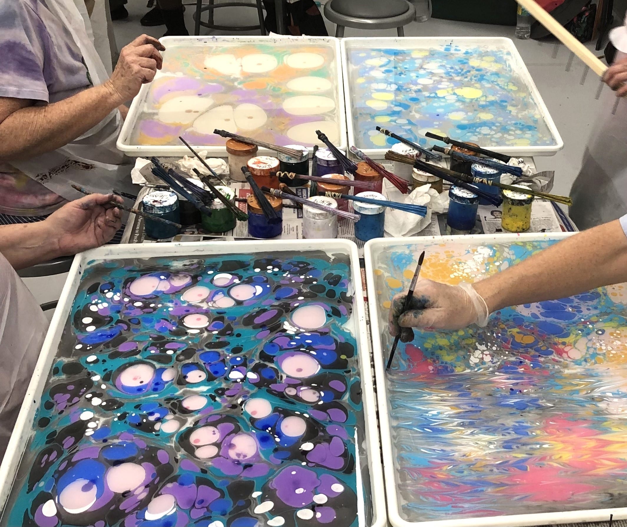 students learning water marbling on metal trays.