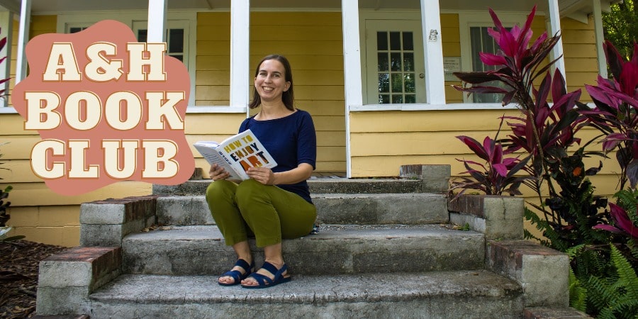 Jessi VanPelt sitting on the steps of a yellow cottage house, holding a book.