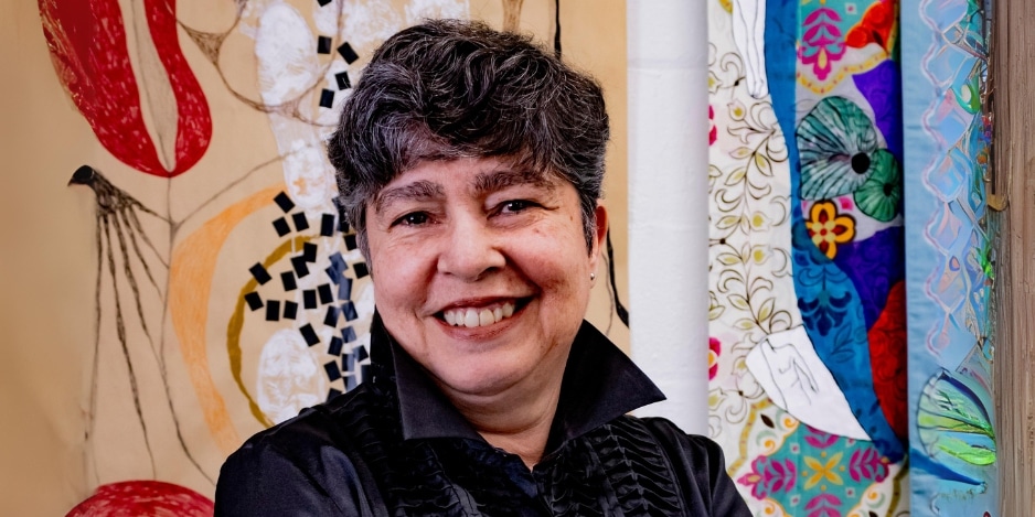 Colorful portrait of Gisela Romero in front of her own artwork.