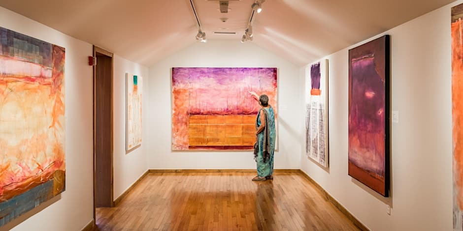 Woman in an open gallery full of colorful paintings.