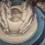 African American hands form a bowl on a pottery wheel